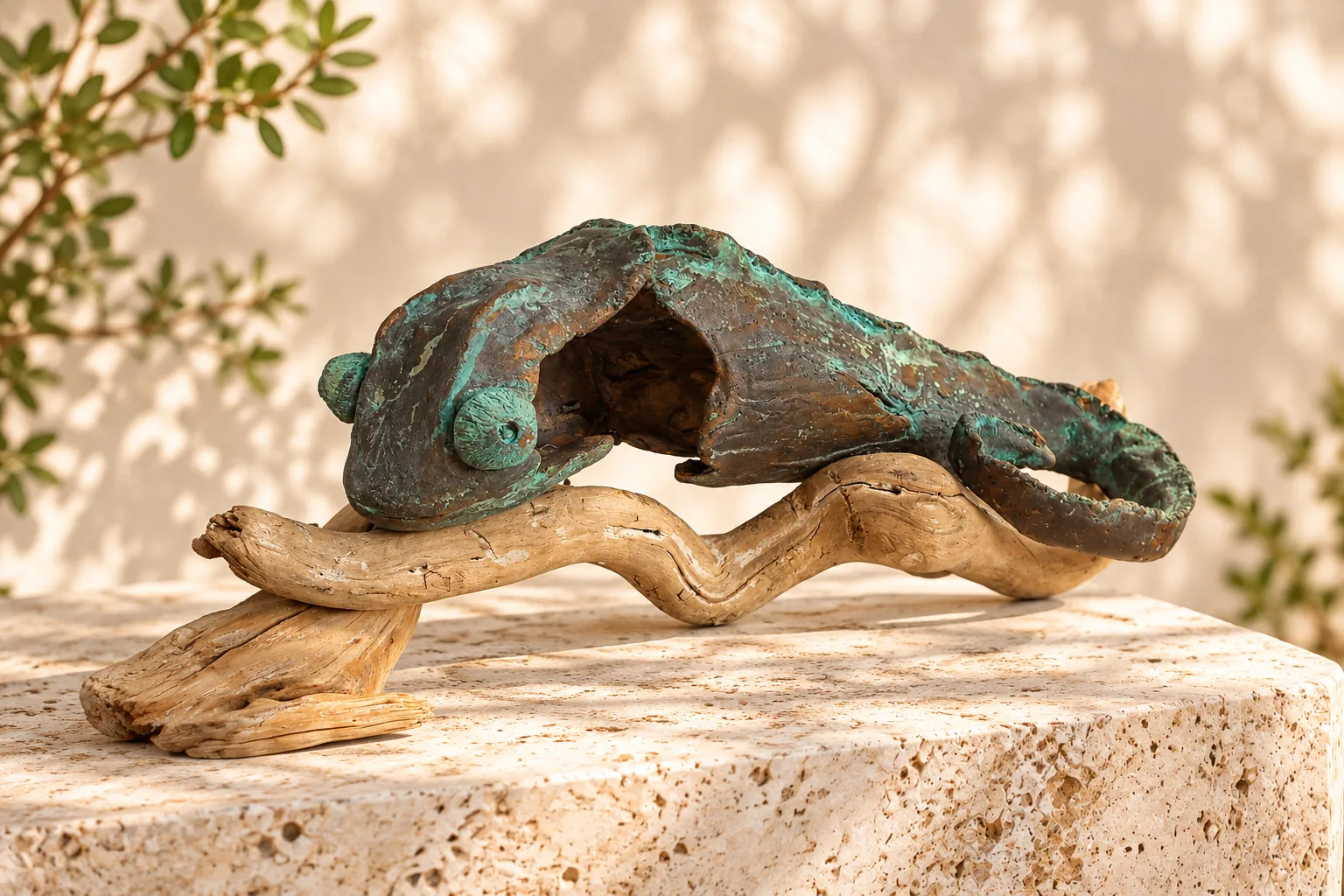 Patinated bronze chameleon sculpture on driftwood, displayed on a travertine plinth in warm sunlight